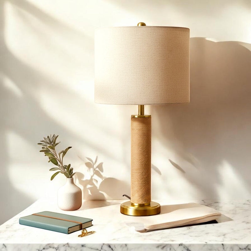 Belcrest rope-wrapped table lamp with brushed brass accents and a natural linen drum shade, casting a warm glow.