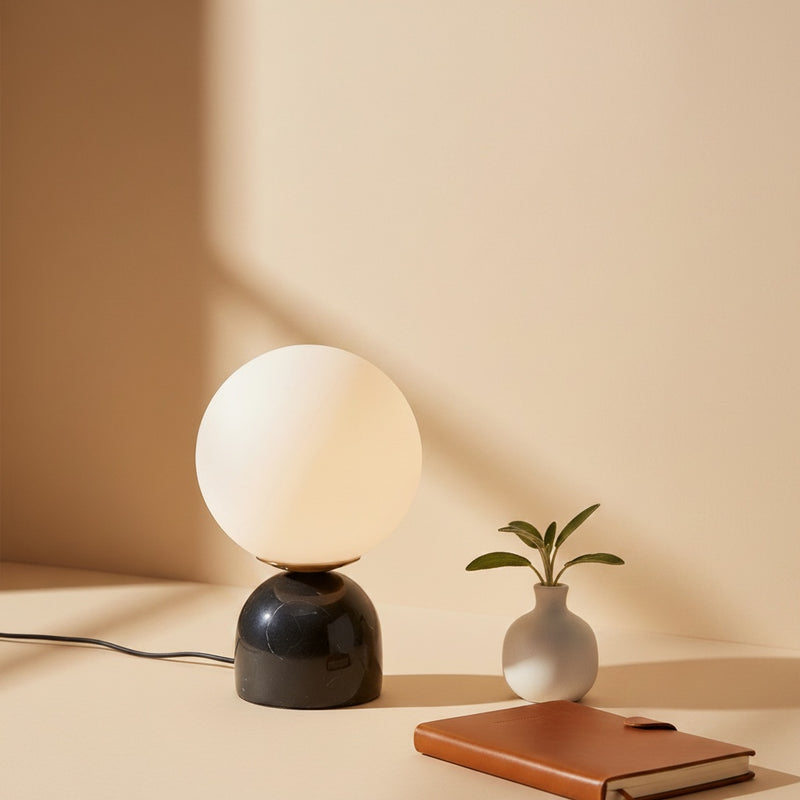 Belcrest opal glass sphere lamp with a solid black marble base and brushed brass accent. Provides soft, diffused light.