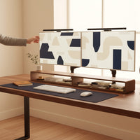 Belcrest screen bar lamp mounted on dual monitors, providing glare-free workspace lighting. Brushed aluminum finish.